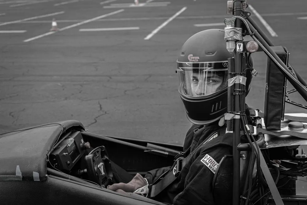 Black and white portrait of the driver in a helmet, seated in the car