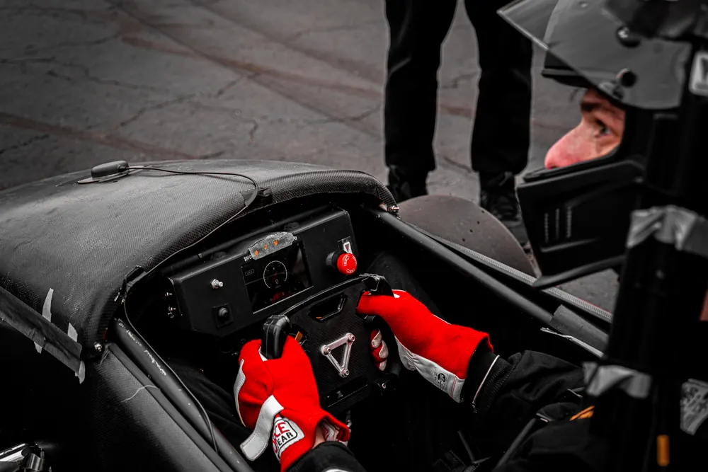The driver's red gloves on the steering wheel in the cockpit