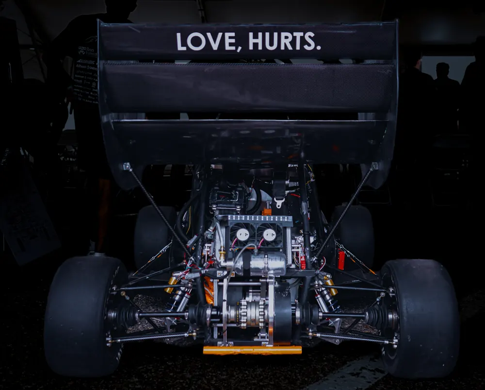 Rear of the car showing the drivetrain under a wing that reads Love, Hurts