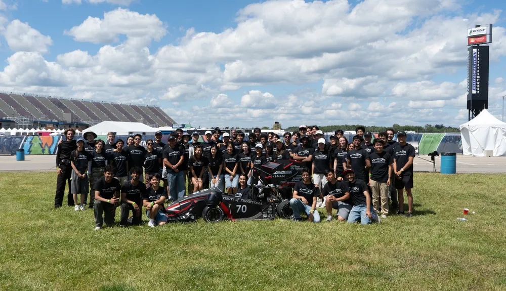 The full Penn Electric Racing team posed with the car on the grass at Michigan International Speedway
